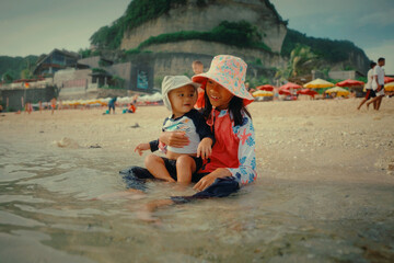 A mother and child enjoy a playful day in the shallow waves at the beach.