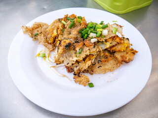 Crispy Thai Oyster Omelette (Hoi Tod) served with fresh bean sprouts and spring onions on a white plate