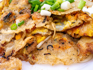 Crispy Thai Oyster Omelette (Hoi Tod) served with fresh bean sprouts and spring onions on a white plate