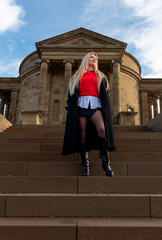 Elegant blonde woman standing on stairs in front of medieval building on a sunny winter day