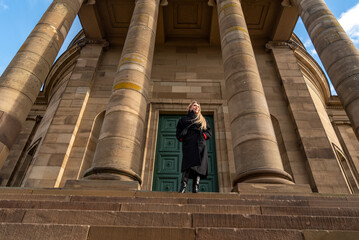 Well dressed woman standing in front of medieval building on a sunny winter day