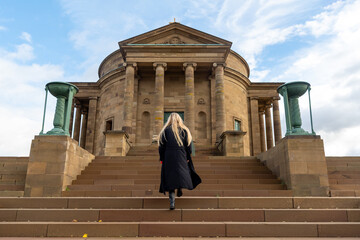 Young woman climbing stairs in front of medieval building