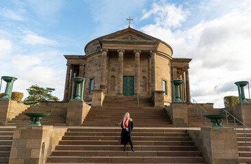 Young woman standing in front of medieval chapel on a sunny winter day