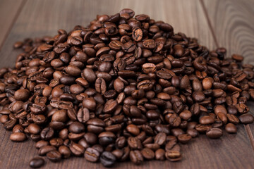 Close up photo of roasted coffee beans on wooden table. Coffee beans heap on wooden background.