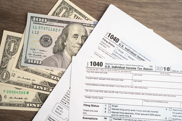 Tax form 1040 U.S. Individual Income Tax Return with dollar banknotes money.