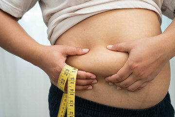 Asian woman use hand to squeeze fat belly big size overweight and obesity.