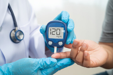 Asian doctor using digital glucose meter for check sample blood sugar level to treatment diabetes.