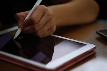 People hand using tablet technology on table at home