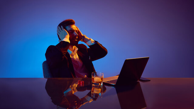 Stressed man reacting emotionally to online casino loss under neon light. Concept of user frustration, risk awareness, emotional tension and basic gambling behavior patterns. - Powered by Adobe