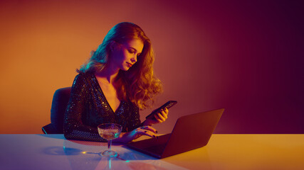 Elegant woman using phone and laptop during online casino play. Concept of digital gambling, calm...