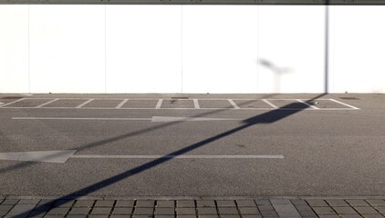 Prefab white concrete wall and street in front with motorcycle parking lines and two directional arrows painted. Background for copy space.