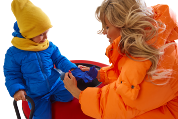 Mother helping child dress for winter tubing activity on transparent background. Concept of parental care, winter safety, outdoor preparation, family support, and calm winter routine.