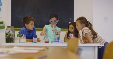 Curious elementary school children doing science experiment in classroom, girl using test tubes and goggles, STEM education, teamwork and learning in modern primary school lab. - Powered by Adobe