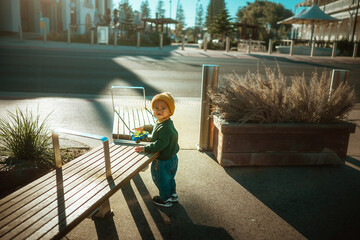 A young child joyfully plays near a bench basking in the warm sunlight, showcasing the essence of...