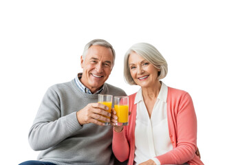 A happy, healthy senior caucasian couple seated on a light sofa, holding vibrant orange juice glasses in a high-key studio, conveying vitality. concept for senior lifestyle advertising