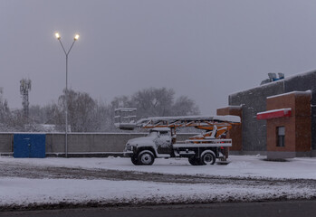 A snow-covered old truck with an electrical installation tower