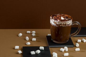 Hot chocolate in a glass mug with marshmallows on a table with dark background