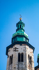 White bell tower and green dome with peak on blue sky background, view from below. Church bell tower on blue sky background