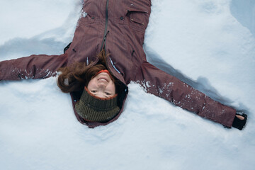 Mid adult woman enjoying of lying on snow in winter