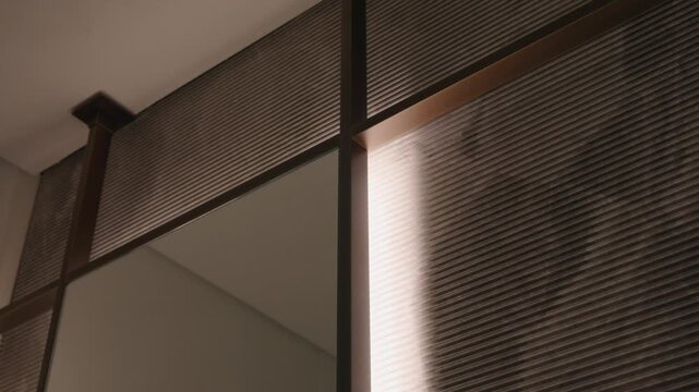 Smooth angled surface meets ribbed texture with soft shadows. Vertical divider adds contrast. Space feels quiet, clean and modern with simple architectural rhythm.