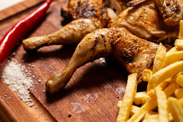 Macro close-up of a juicy grilled chicken leg with crispy French fries, ready to eat.