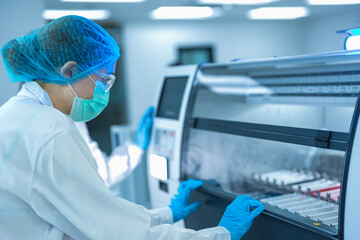 A team of pathologists processes samples using an automated staining machine. They are conducting...