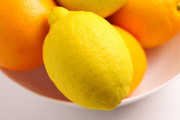 Lemons and oranges in a white dish. Fresh citrus fruits.
