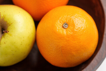 Natural texture of citrus peel and apple skin of fresh fruits close-up in a wooden bowl