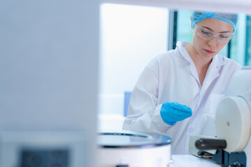 Focused Caucasian female scientist with red hair preparing tissue slide at microtome. Young...