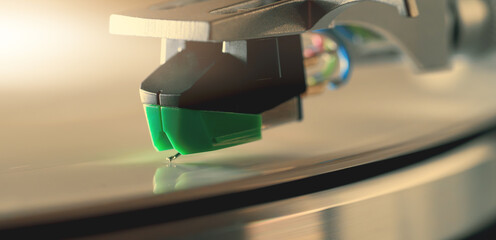 Turntable needle playing vinyl record surface, macro shot. Analog music and vintage audio.