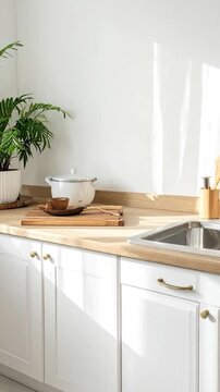 Modern kitchen corner with white cabinets, wooden countertop, greenery, and stainless steel sink