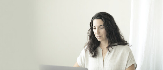 Female patient sits at home having a virtual medical consultation with a doctor through a video call on her laptop.
