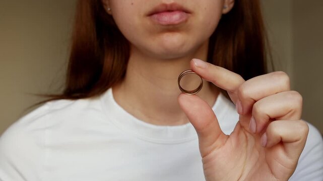 A woman holds a wedding ring, a broken heart. Betrayal, divorce, and letting go.