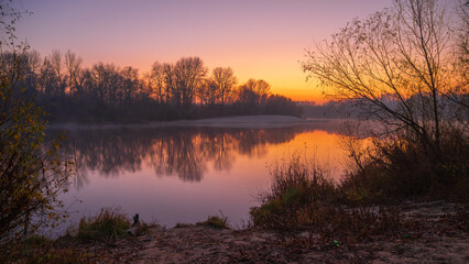 autumn foggy sunrise on the river around forest
