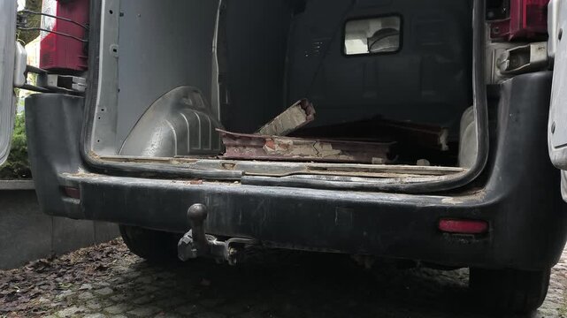 Załadunek drobnego złomu do małego samochodu dostawczego. Wrzucanie drobnych element&oacute;w stalowych, pozostałości po remoncie budynku, w celu dostarczenia ich do punktu skupu złomu.