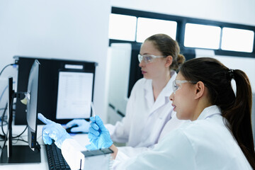 Team of female scientists analyzing digital pathology slides on computer. Caucasian and Asian researchers reviewing histology data for medical diagnosis in modern lab.