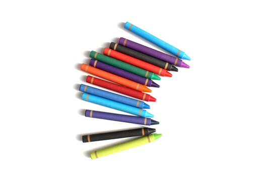 There are many multi-colored wax crayons lying on a white background.