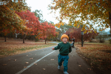 young child playing in fall leaves, energetic toddler enjoying autumn day outdoors