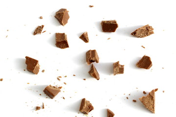 There are many small pieces of chocolate lying on a white background.