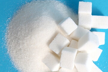 There are cubes of refined sugar lying on a pile of granulated sugar.	
