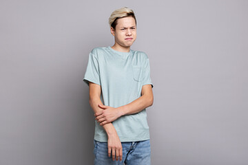 Teenage boy showing disgust and displeasure while reacting to something unpleasant indoors, emotional studio portrait expressing negative feelings, rejection, discomfort and aversion