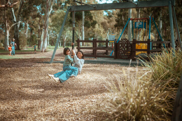 children enjoying playground together, children joyfully swinging on playground with trees