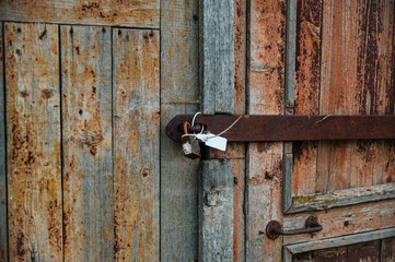 The old wooden door is sealed with a seal and locked with a rusty lock