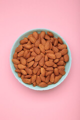 Almonds in mint bowl on pink background