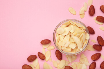 Fresh almond flakes and nuts in bowl on pink background