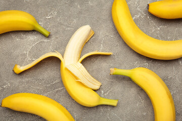 Open ripe banana on grey concrete background.