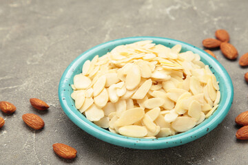 Fresh almond flakes in plate on grey concrete background