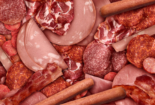 Processed Meats Background as an assortment of sliced and cured meat as deli style ham salami prosciutto, and hot dogs as cold cuts charcuterie.