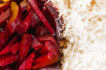 Macro texture of sliced red boiled beetroot and white grated horseradish. Close-up of fresh salad ingredients contrast. Healthy root vegetable food background
