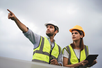 Two construction workers wearing safety gear and pointing at something